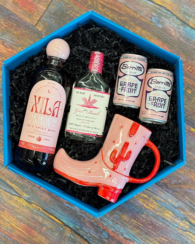 Gift set with bottles and a mug in a blue box on a wooden surface