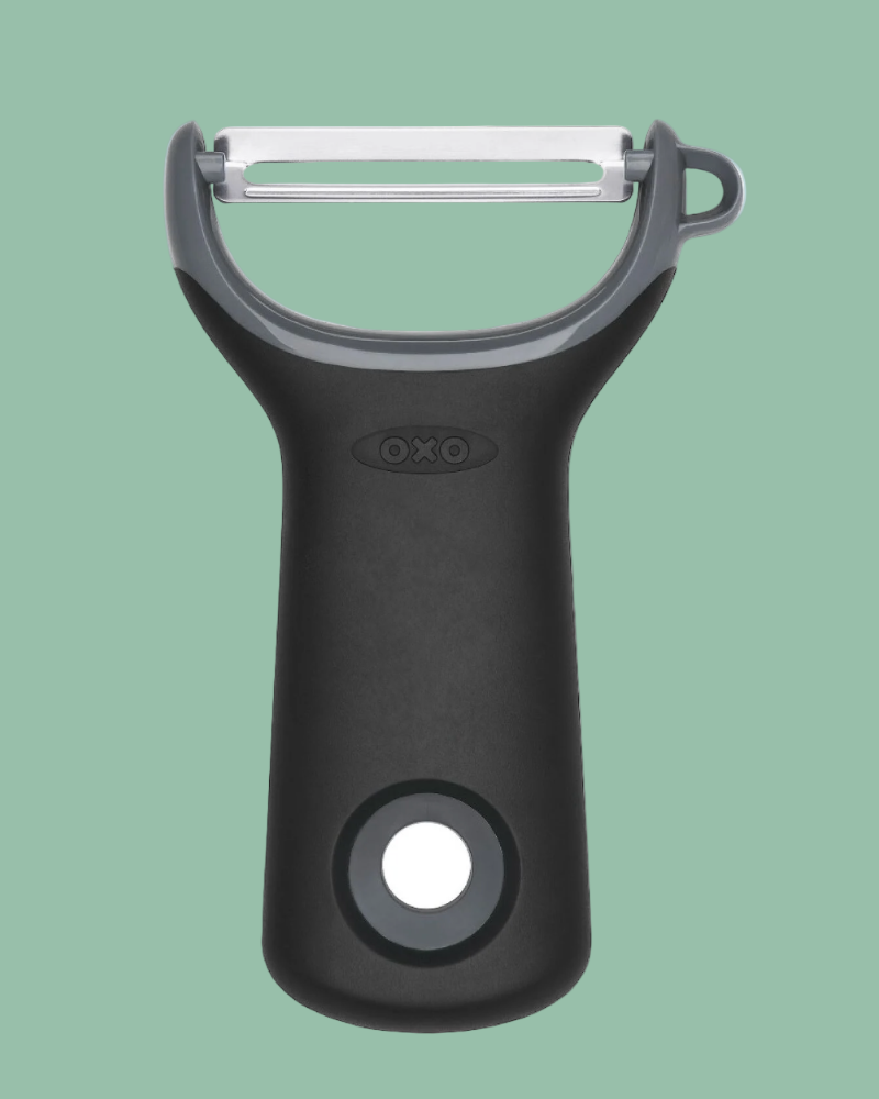 Black OXO peeler on a green background