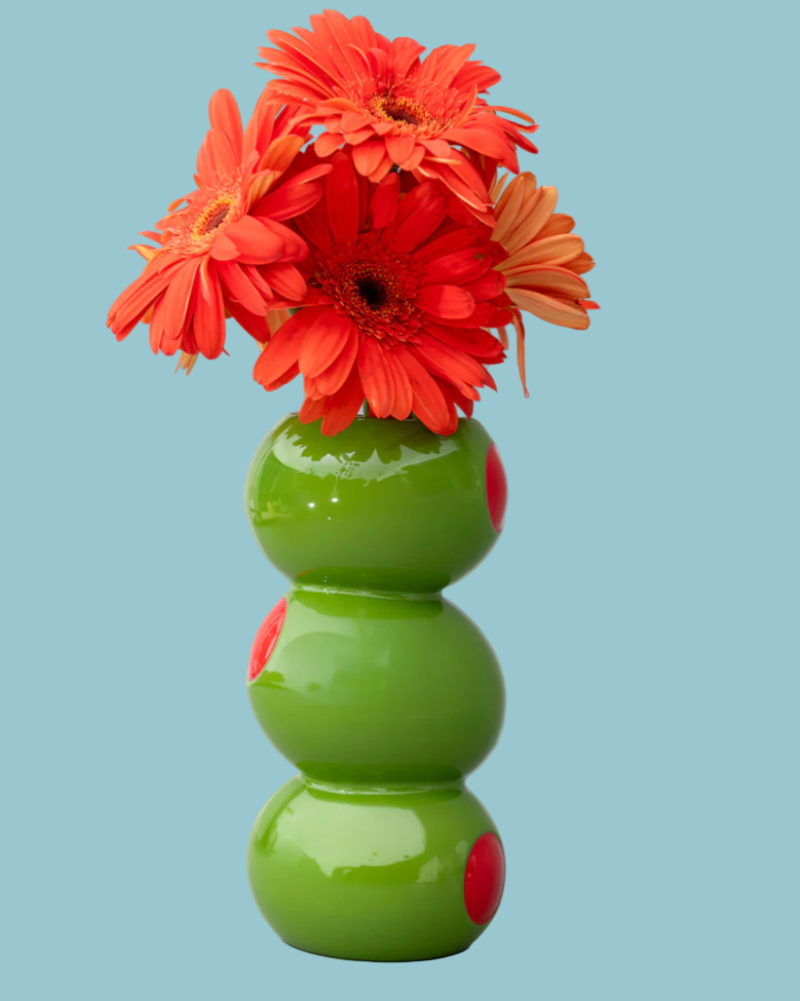 Green vase with red flowers on a light blue background