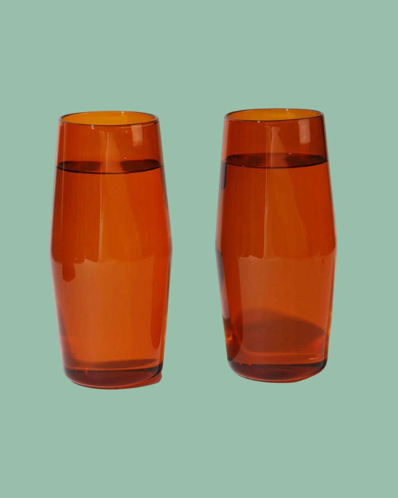 Two orange glass tumblers on a light green background