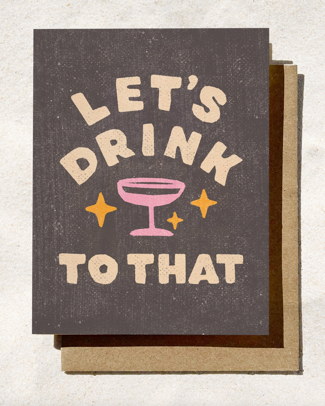 Greeting card with 'Let's Drink to That' text and drink glass illustration on a textured background