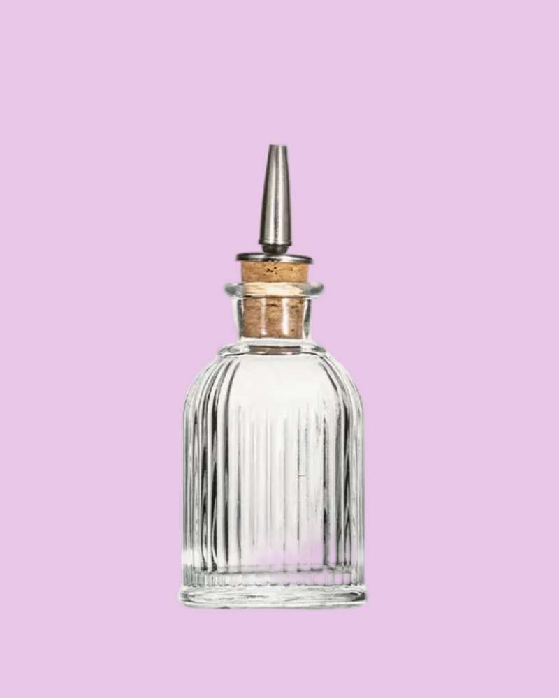 Clear glass bottle with wooden cap on a pink background