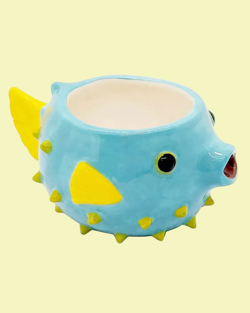 Blue and yellow puffer fish-shaped ceramic mug on a white background