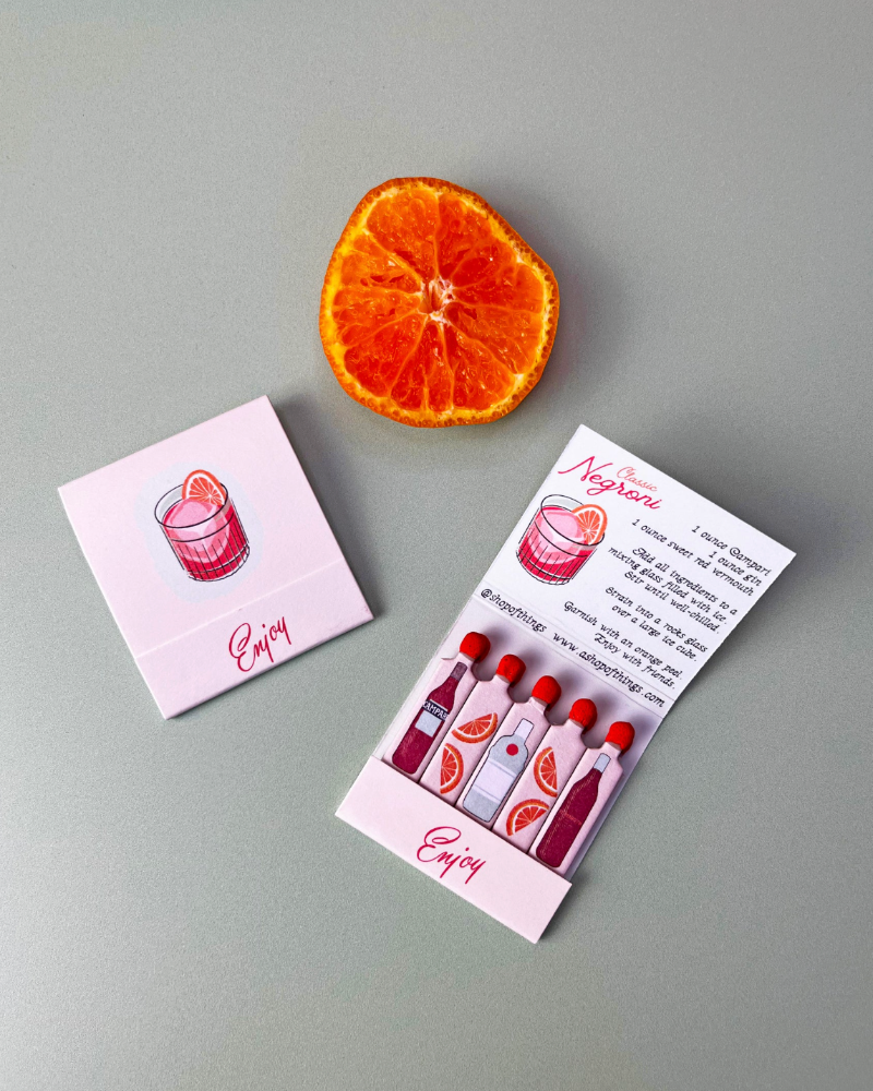 Two business cards with a drink illustration and an orange slice on a gray background