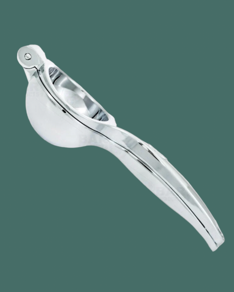 silver juice hand squeezer on a green background