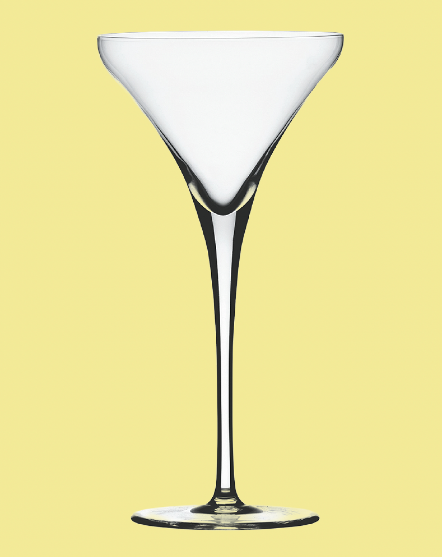Clear martini glass on a light yellow background