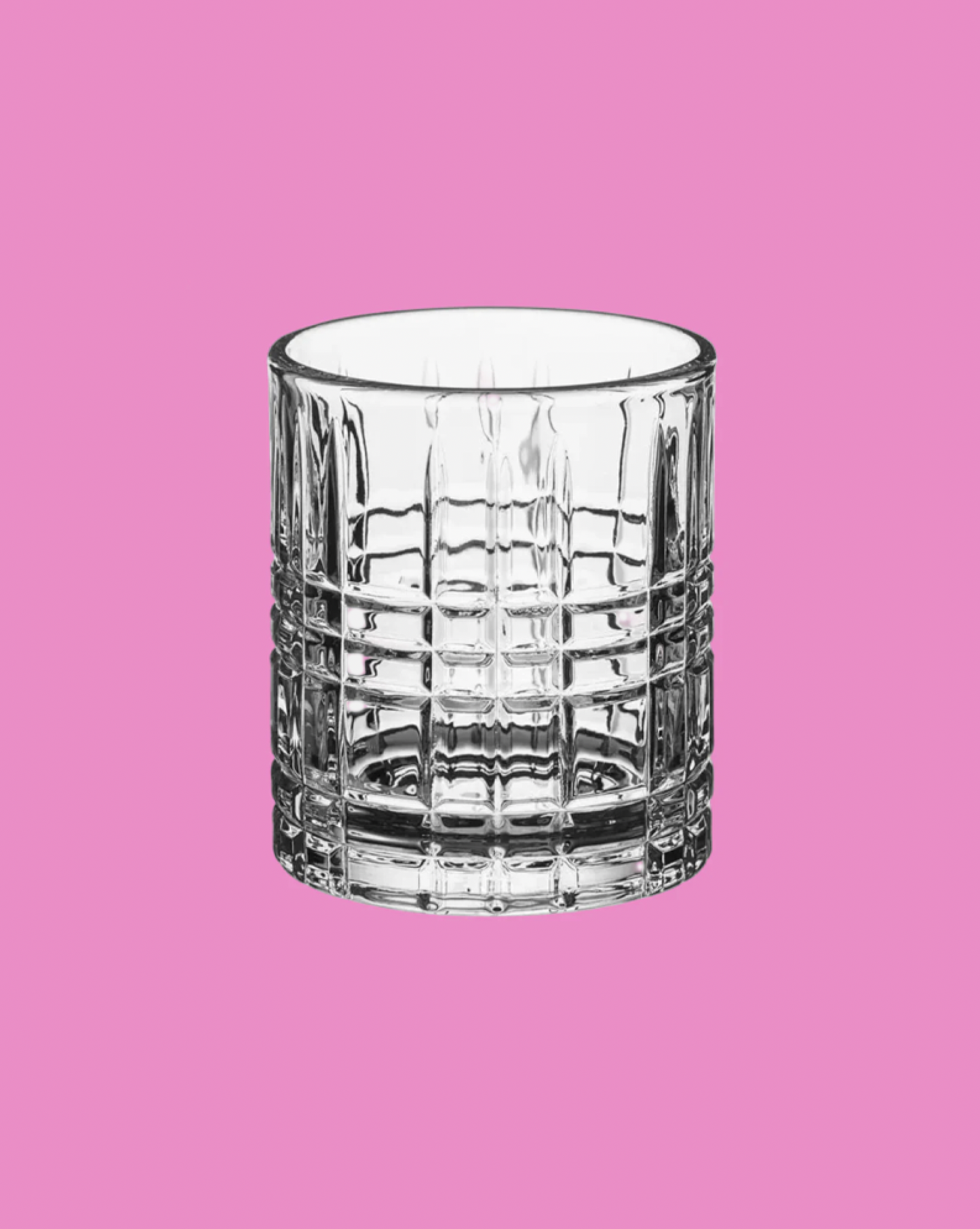 Clear glass tumbler on a pink background