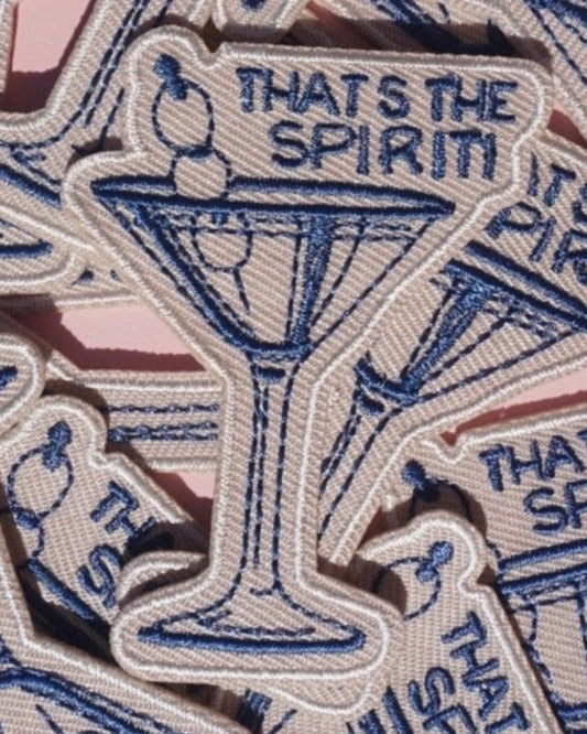 Patch with a martini glass design and text 'THAT'S THE SPIRIT' on a pile of similar patches.