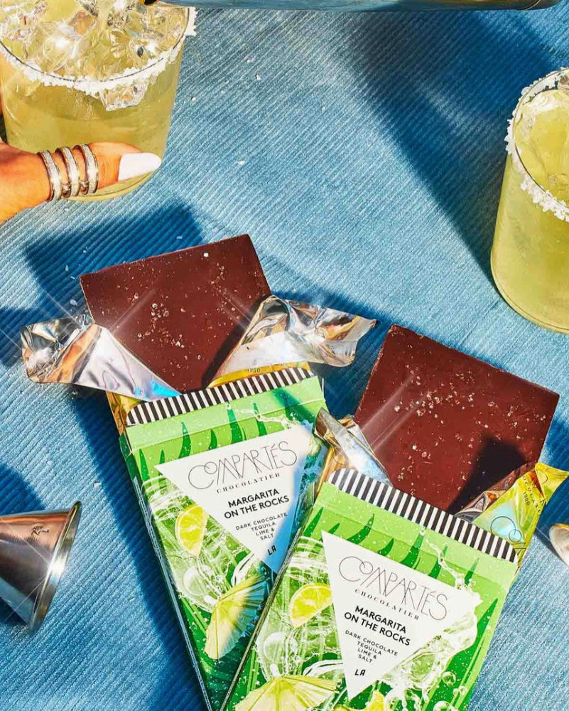 Cavie's Margarita on the Rocks chocolate bars with drinks and jiggers on a blue surface