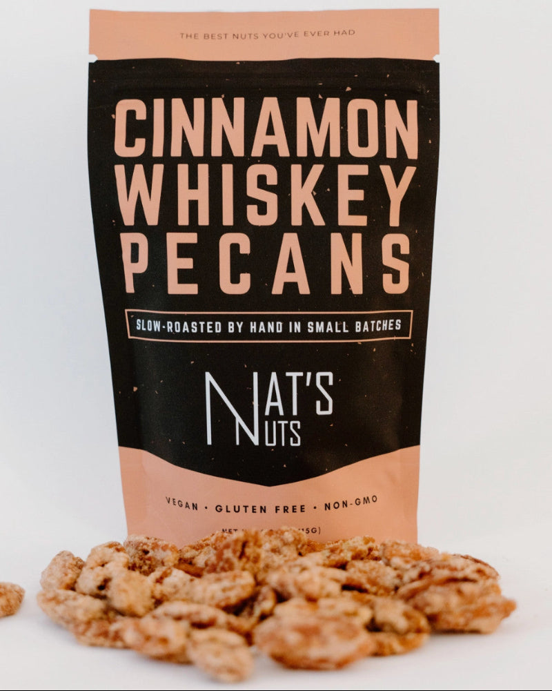 Bag of Cinnamon Whiskey Pecans from Nat's Nuts with pecans in front on a white background
