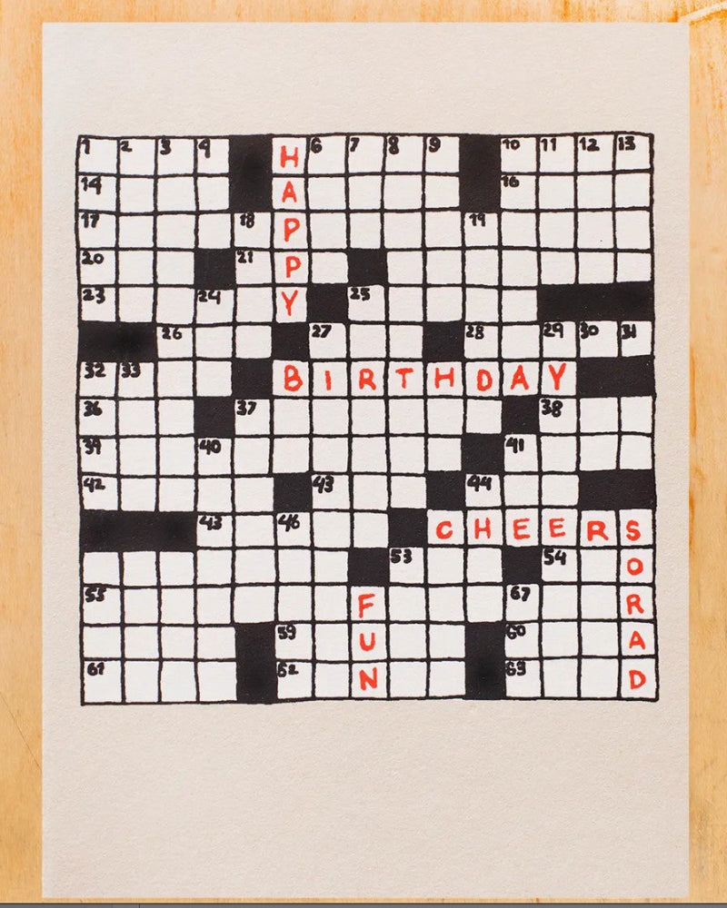 Crossword puzzle with 'Happy Birthday' and other words on a wooden surface