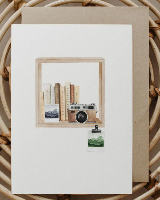 Framed artwork with a camera and books on a white background