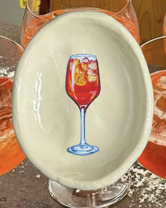 Decorative egg with a wine glass design on a table with drinks in the background