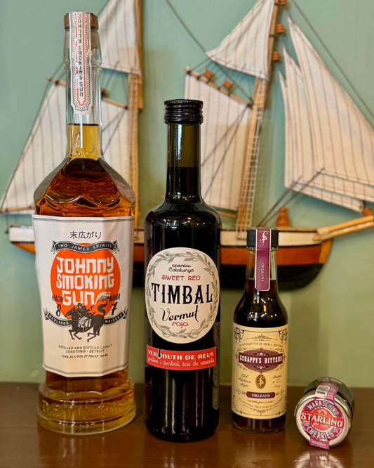 Three bottles of alcohol with visible labels on a wooden surface, with a decorative boat model in the background.