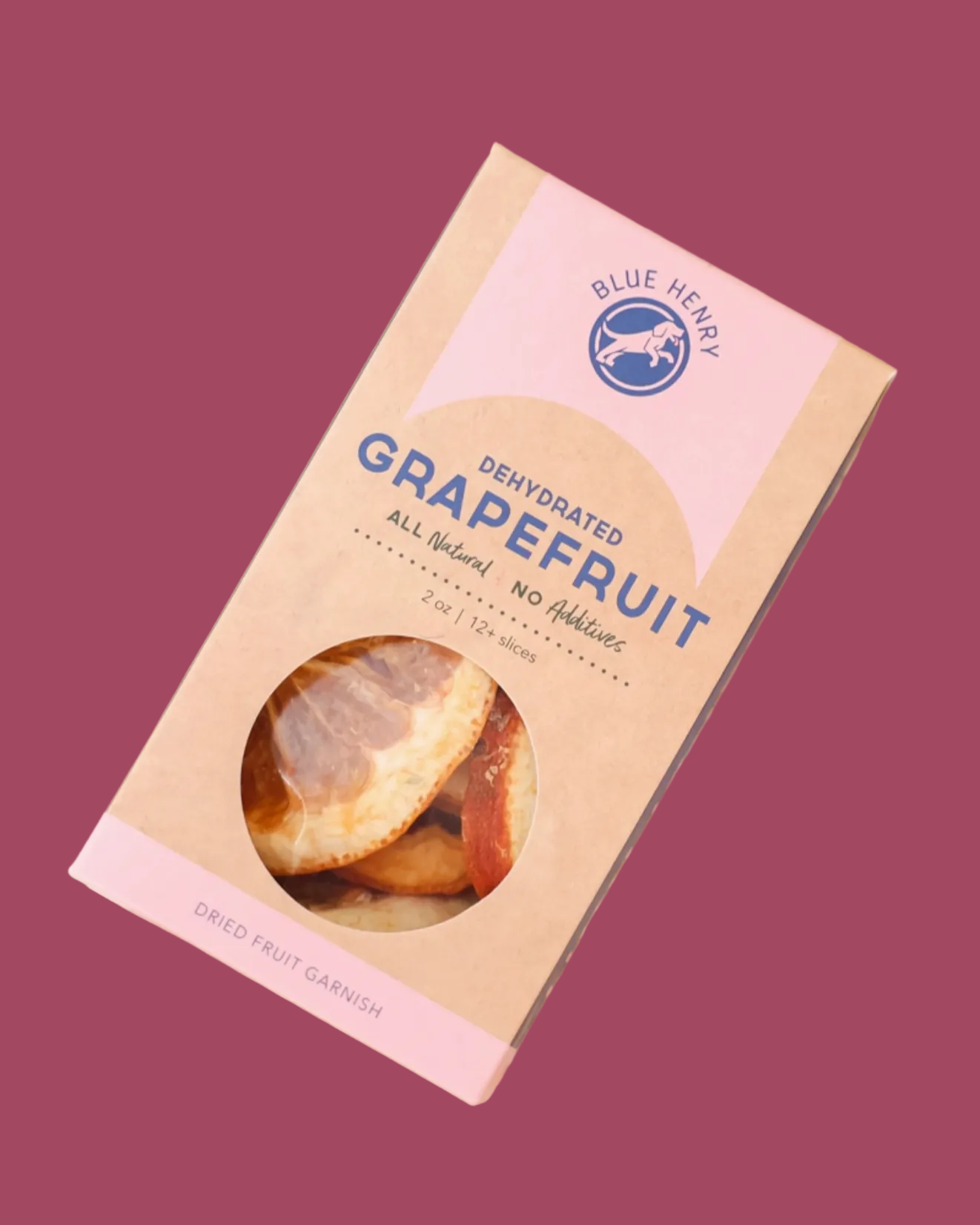 A package of Blue Henry Grapefruit Dried Fruit Garumush, shown in a kraft paper box with pink accents and a clear window displaying the dried fruit inside, set on a wooden surface with dried grapefruit slices.