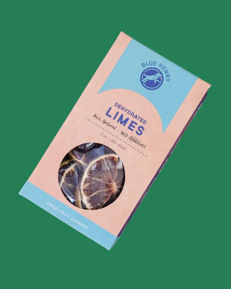 A package of Blue Henry Dehydrated Limes surrounded by sliced dried lime slices on a wooden surface.