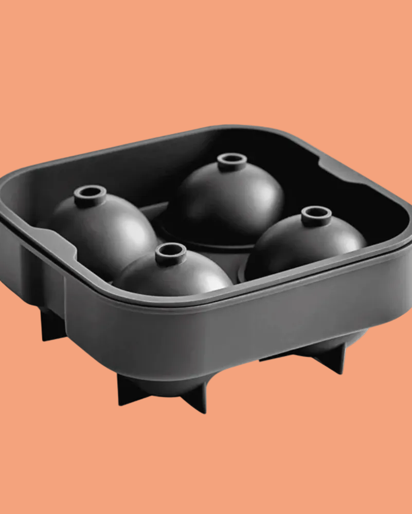 A black silicone mold tray with four dome-shaped cavities, shown on a solid peach-orange background.