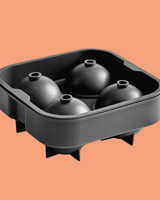A black silicone mold tray with four dome-shaped cavities, shown on a solid peach-orange background.