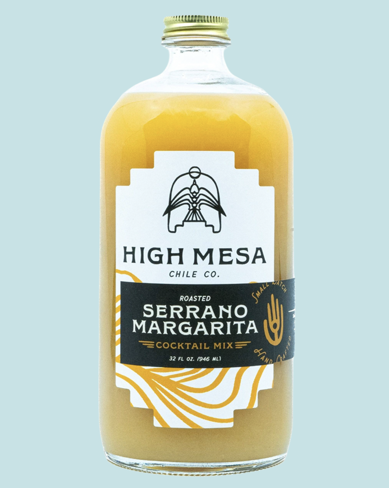 A 32 fl oz glass bottle of High Mesa Chile Co. Roasted Serrano Margarita cocktail mix, filled with a golden yellow liquid and featuring a white and black label with gold accents, set against a solid light blue background.