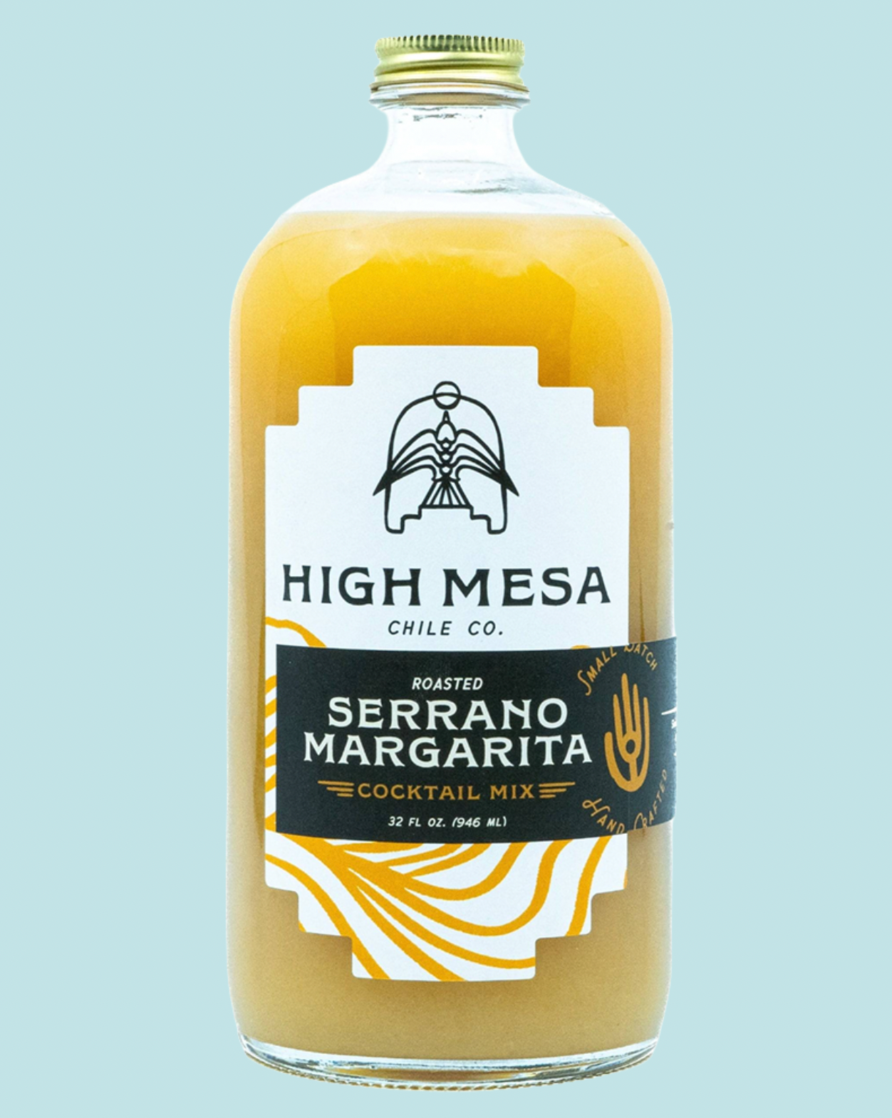 A 32 fl oz glass bottle of High Mesa Chile Co. Roasted Serrano Margarita cocktail mix, filled with a golden yellow liquid and featuring a white and black label with gold accents, set against a solid light blue background.