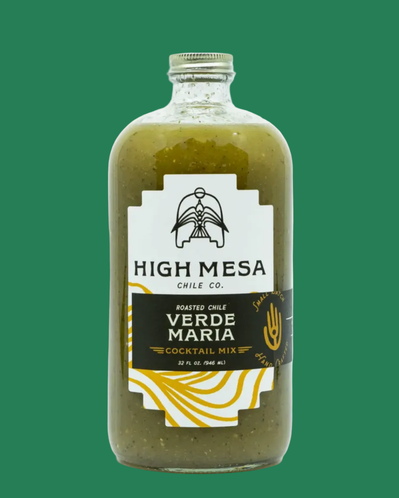 A glass bottle of High Mesa Chile Co. Verde Maria Roasted Chile Cocktail Mix, filled with a textured olive-green sauce, featuring a white and black label with gold accents, on a white background.