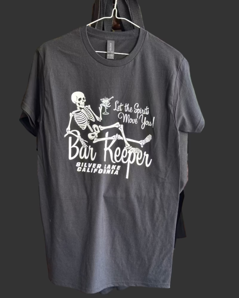 Black t-shirt with skeleton design and text on a hanger in a store.