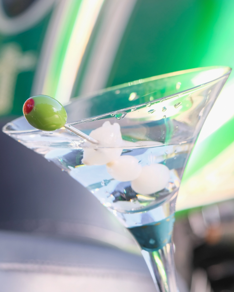 Martini glass with a olive and onions on a  blurred green background