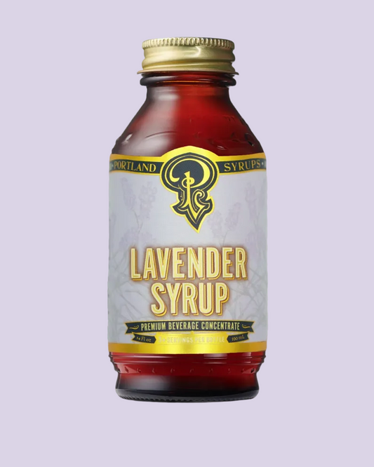 A bottle of Portland Lavender Syrup with a gold cap and a light gray label featuring a gold and black logo, set against a plain white background.