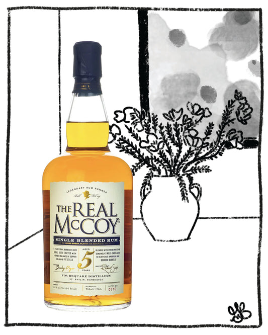 Bottle of 'The Real McCoy' single blended rum with a decorative vase and flowers in the background.