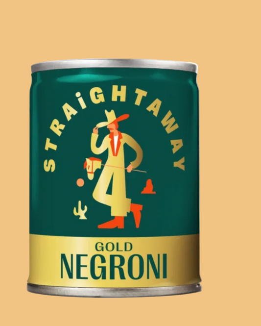 A single canned food product on a solid warm beige background. The can is dark teal-green with a gold band at the bottom and a stylized illustration of a cowboy in a yellow suit and red hat, with the words 'STRAIGHTAWAY' arched above and 'GOLD NEGRONI' on the can.