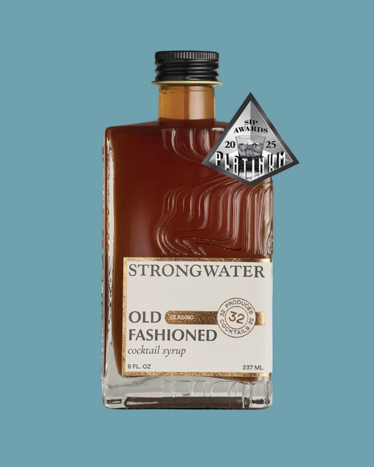A bottle of Strongwater Old Fashioned cocktail syrup with a black cap and a gold and white label, featuring a silver 'Six Awards Platinum' badge on the side, set against a plain white background.