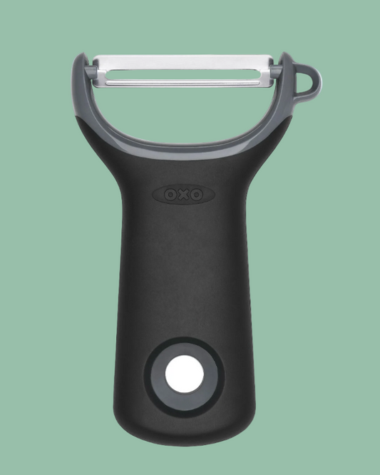 Black OXO peeler on a green background