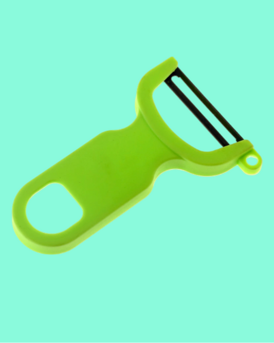 Green vegetable peeler on a solid light blue background