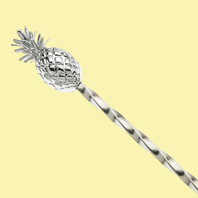 Silver pineapple-shaped stirrer on a light yellow background
