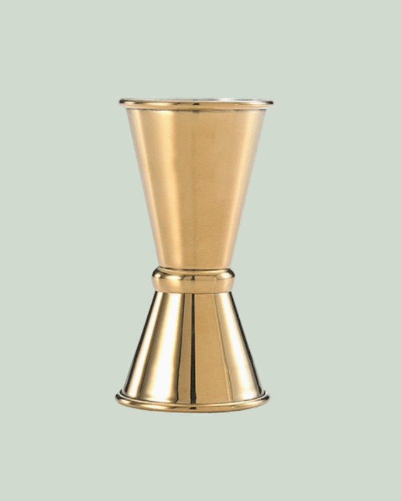 Gold metal jigger on a light green background