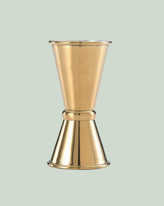 Gold metal jigger on a light green background