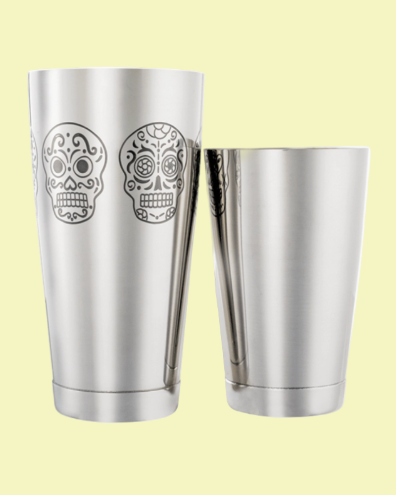 Two stainless steel tumblers with sugar skull designs on a light yellow background