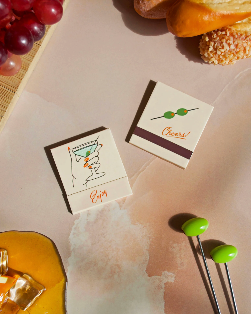Two small cards with drink illustrations on a table with bread and grapes.