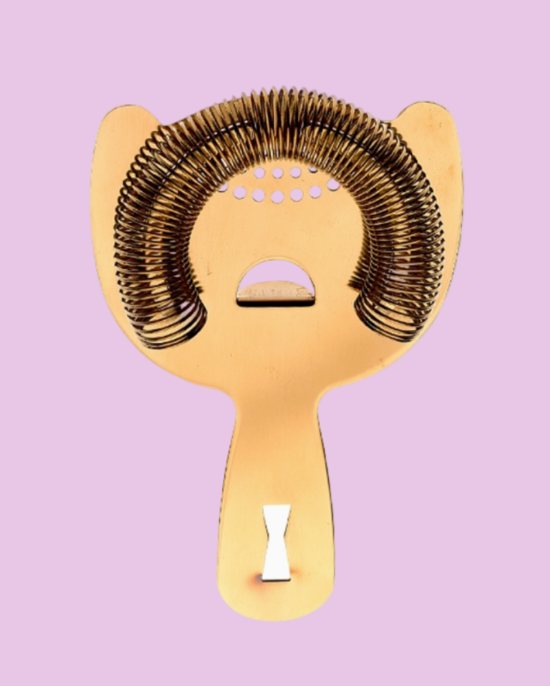 Gold and bronze bar strainer on a pink background