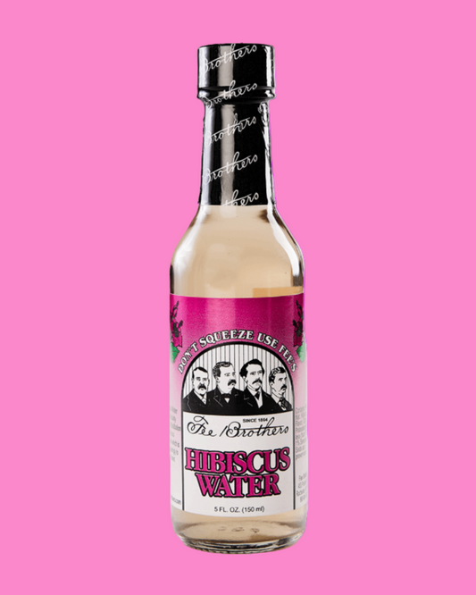 Bottle of Heiress Water with a pink label on a pink background