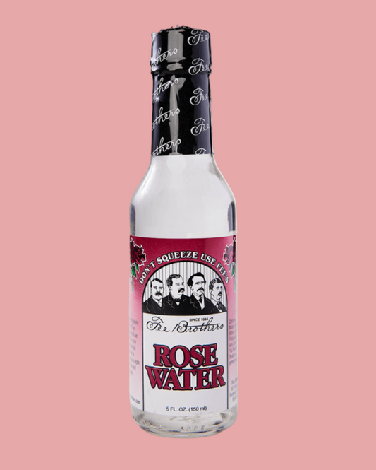 Bottle of rose water with a pink label on a pink background