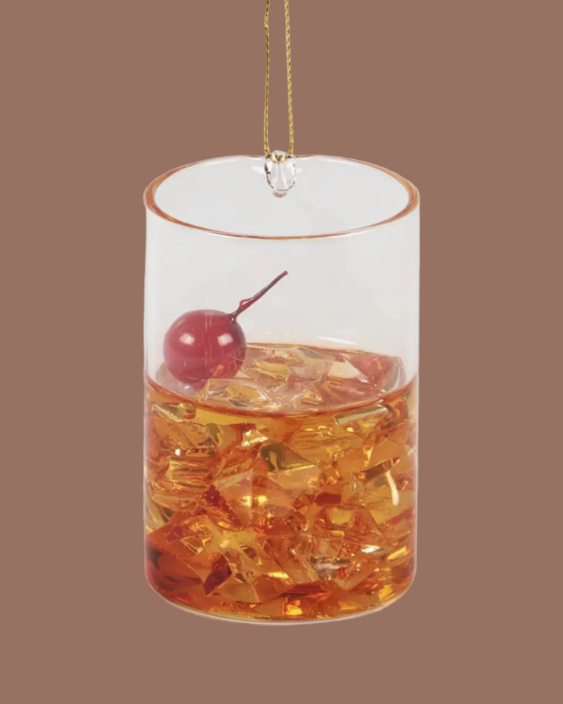 Decorative glass ornament with a cherry on top against a brown background