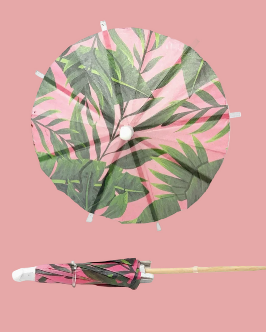 Tropical leaf-patterned cocktail umbrella with sticks on a white background