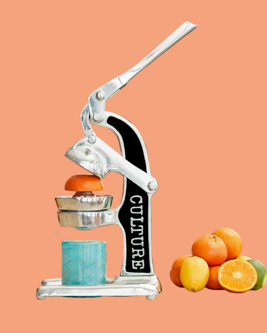 Manual juicer with oranges on a peach background