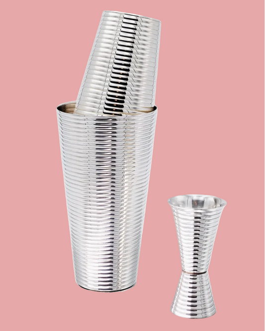 Stacked silver metal cups on a pink background