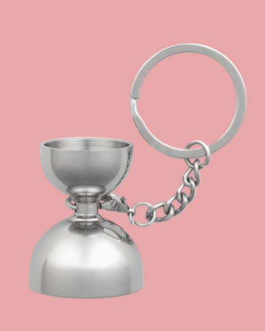 Metallic keychain with a small cup-like structure on a pink background