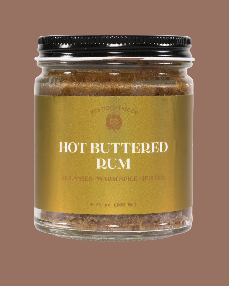 Jar of hot buttered rum mix with a gold label on a brown background