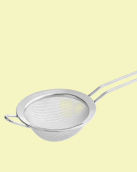 Metal mesh strainer with handle on a light yellow background
