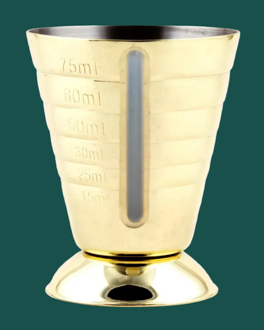 Gold measuring cup with measurement markings on a green background