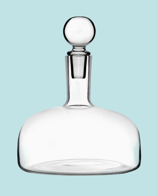 Clear glass decanter with a silver stopper on a light blue background